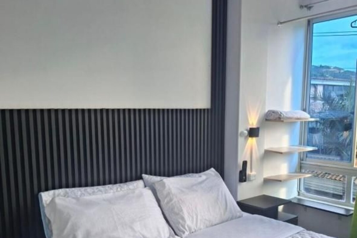 Een moderne slaapkamer met een bed, nachtkastjes en een raam met uitzicht.
