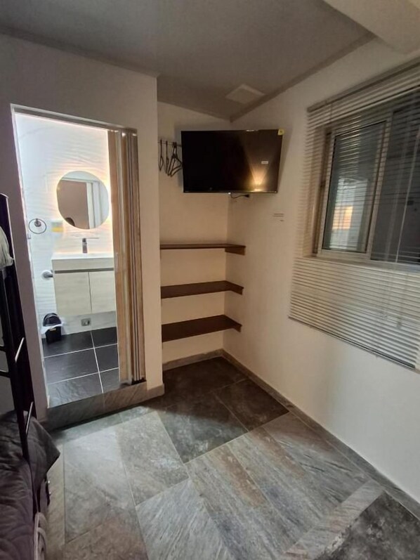 Un intérieur moderne avec un téléviseur à écran plat fixé au mur, un escalier et une fenêtre équipée de stores.