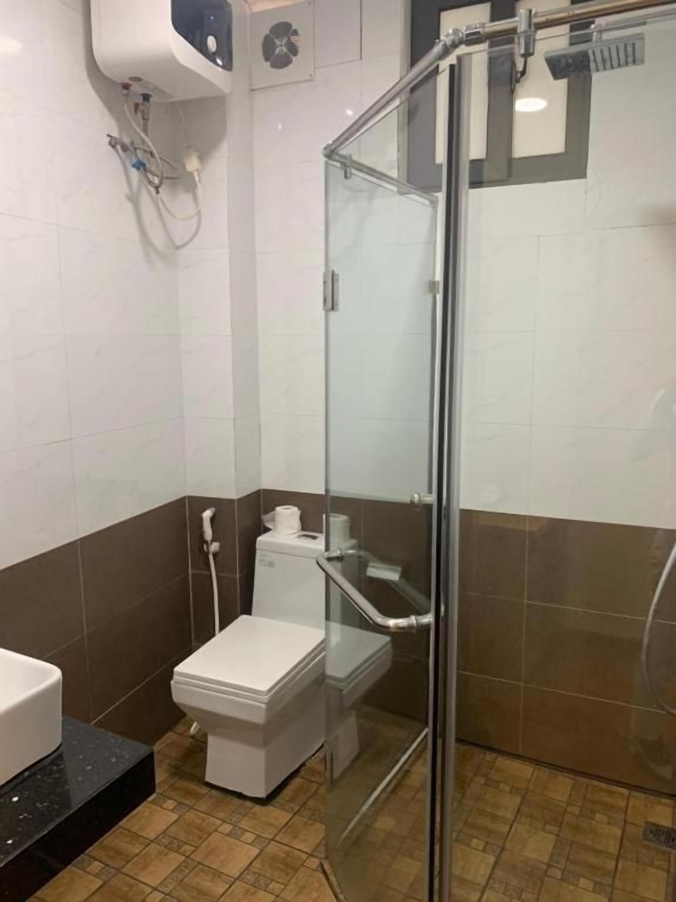 Un baño con ducha envuelta en vidrio, inodoro y lavamanos.