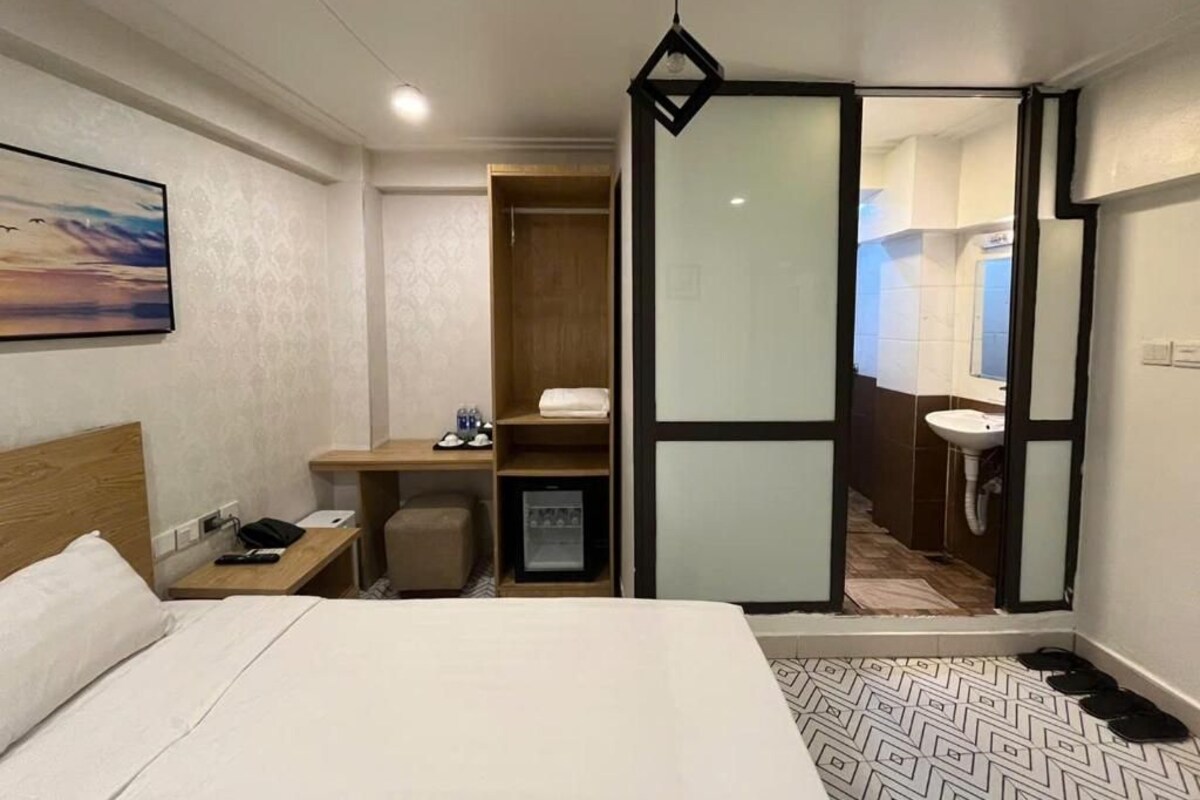 A hotel room with a bed, a desk, a wardrobe, a bathroom, and a painting on the wall.
