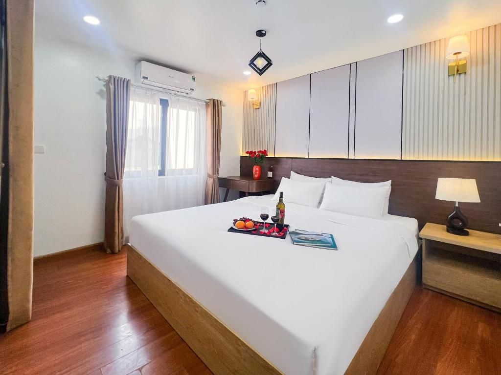 A hotel room with a large bed, a bedside table with a lamp, and a wall-mounted air conditioner.