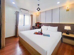 A hotel room with a large bed, a bedside table with a lamp, and a wall-mounted air conditioner. - Hanoi Valley Hotel (Ha Noi)
