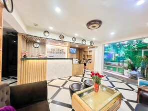 A hotel reception area with a reception desk, a clock, and a television. - Hanoi Valley Hotel (Ha Noi)