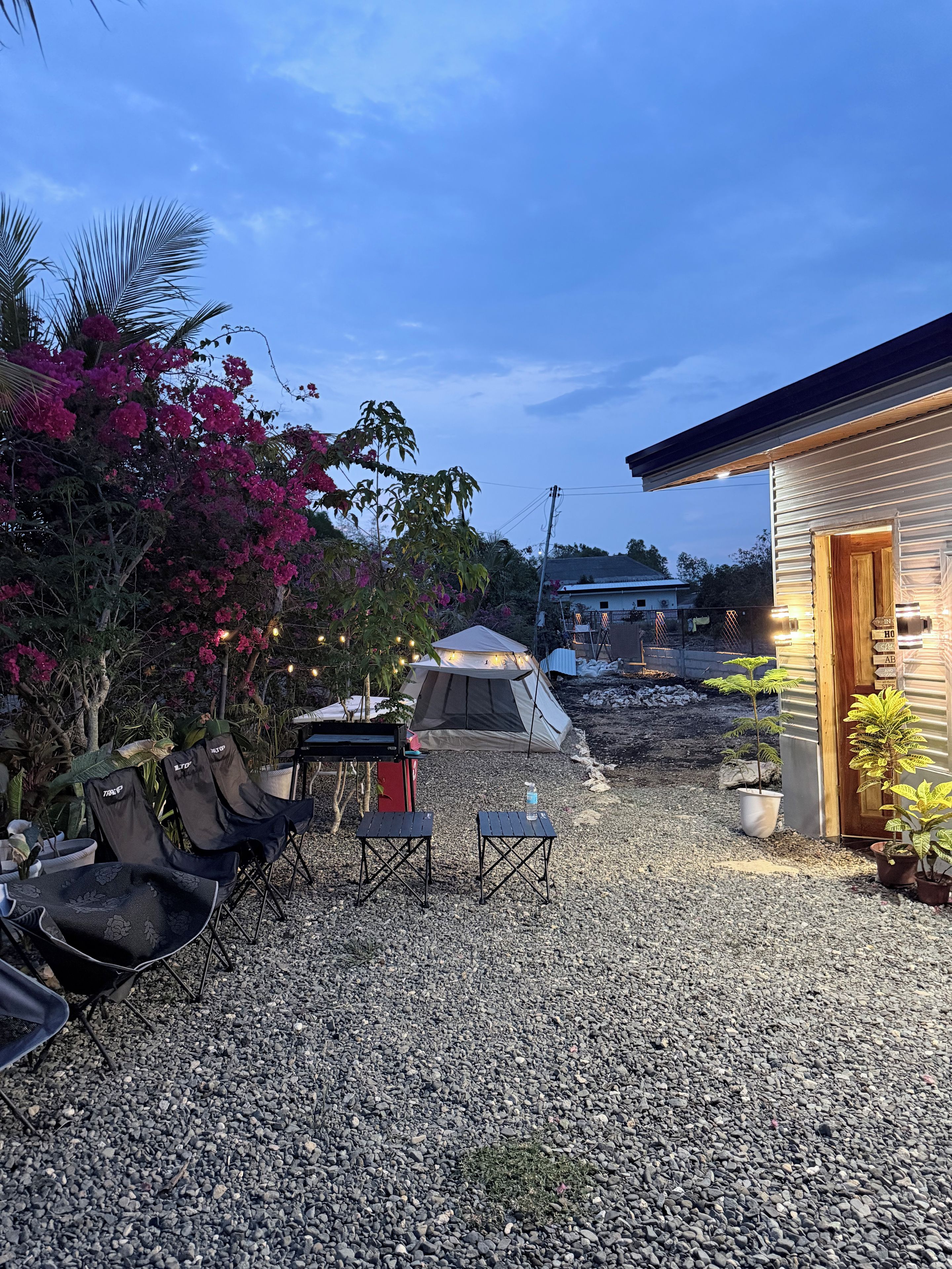 Eine gepflasterte Terrasse mit Sitzgelegenheit im Freien, einem Zelt und einem Gebäude mit einer Tür.