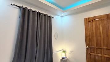 Une chambre d’hôtel avec un lit, une porte en bois, une table de chevet avec une lampe et un luminaire au plafond.