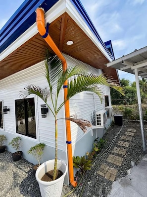 A house with a white exterior, a wooden roof, and a central orange pipe.