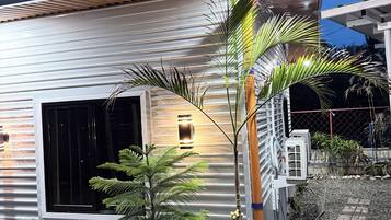 Una casa moderna con un amplio ventanal, plantas en macetas y un camino de grava.
