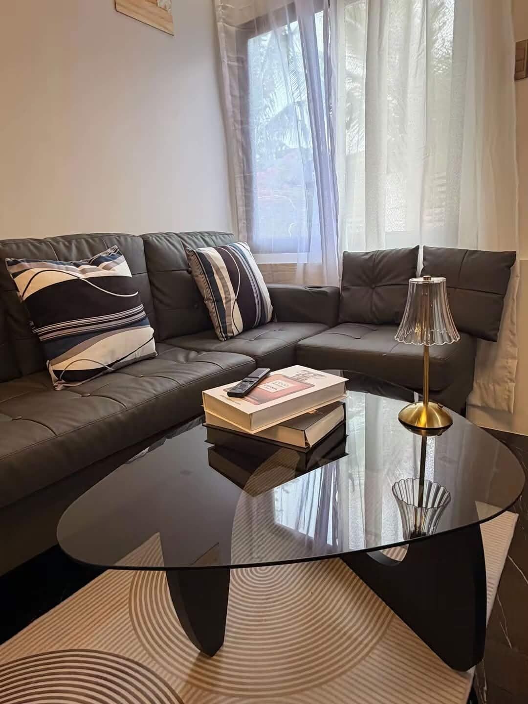 Ein modernes Wohnzimmer mit einem schwarzen Ledersofa, einem Glastisch und einer Lampe.