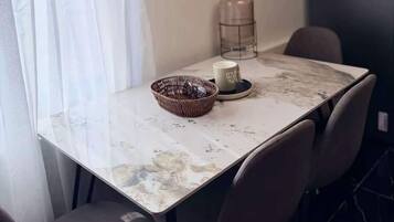 Un comedor con una mesa, sillas, una vela, un tarro de vidrio y una cesta.