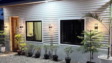 Una casa moderna con camino de grava, plantas en macetas y una puerta de madera.