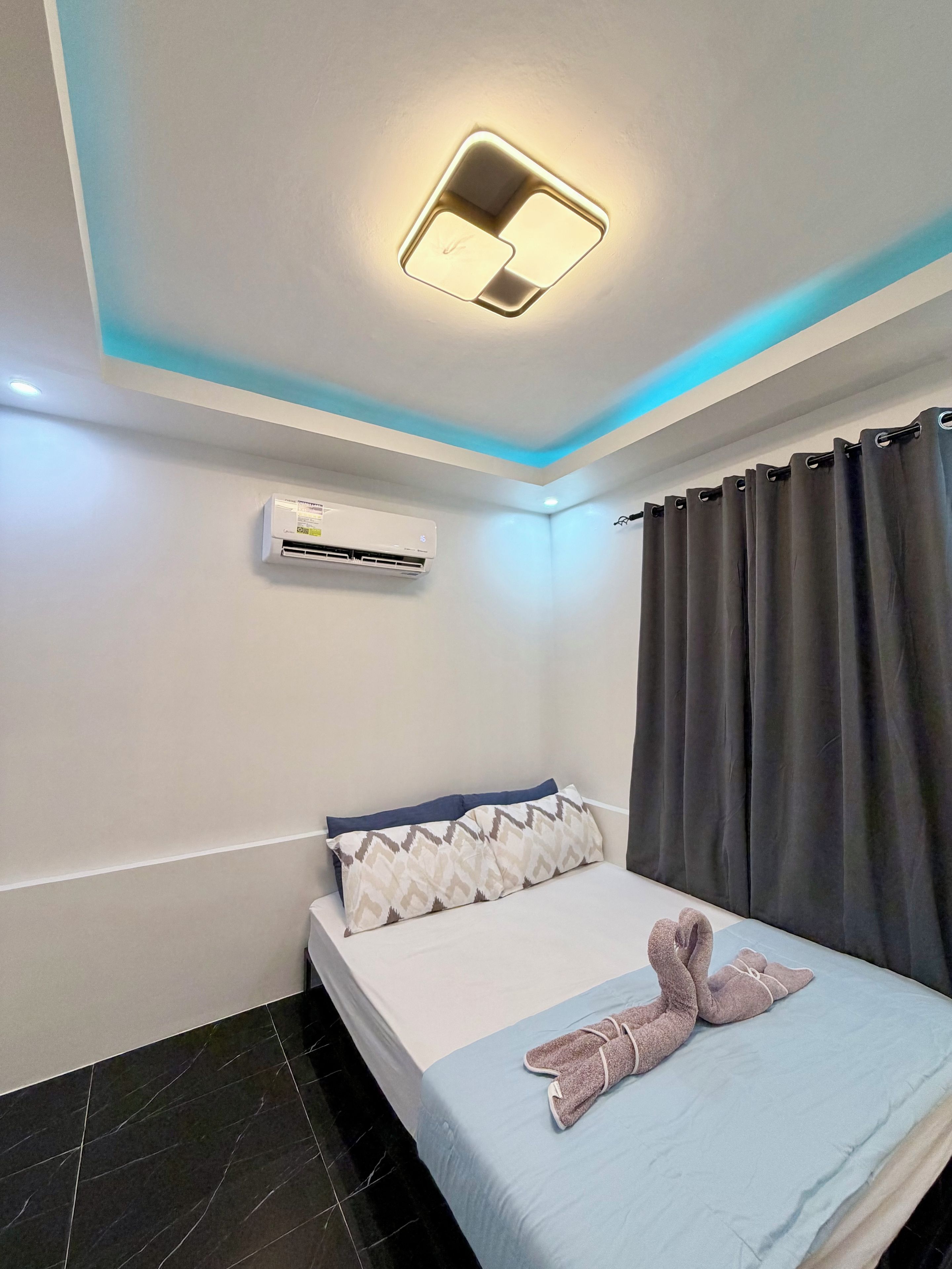 Een hotelkamer met een bed, airconditioning, een lamp en een gordijn.