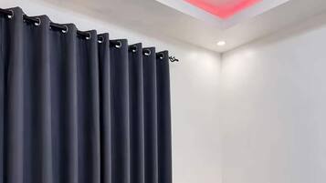 Un dormitorio con cama, mesita de noche, lámpara y ventana con cortinas.