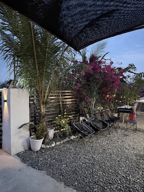 An outdoor seating area with a gravel ground, potted plants, and a wooden fence.