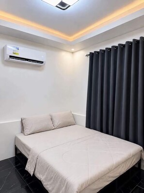 A modern bedroom with a bed, an air conditioning unit, and a curtain.
