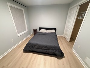 A bedroom with a bed, a nightstand, a window with blinds, and a closet with hanging clothes. - Soothing room in a quiet house near Penn State (State College)