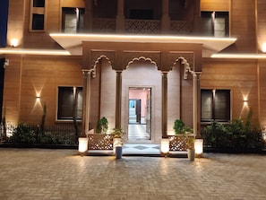 A hotel entrance with a traditional archway, potted plants, and a checkered floor.