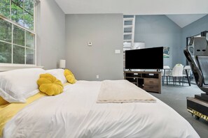 Ein modernes Schlafzimmer mit einem großen Bett, einem Flachbildfernseher, einem Schreibtisch und einem Stuhl.