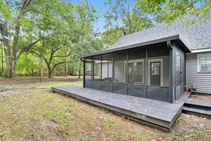 Ein modernes Haus mit überdachter Terrasse, umgeben von Bäumen.