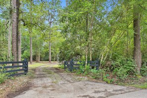 A forested area with a gravel path leading to a gate. - 5BR All King Beds Nature Mansion Retreat (Covington)