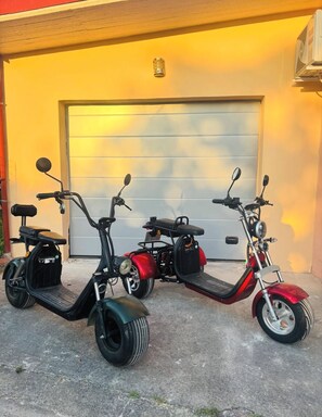 Two electric scooters parked in front of a garage. - Pancho Villa Family Apartments (Kallithea Pieras)