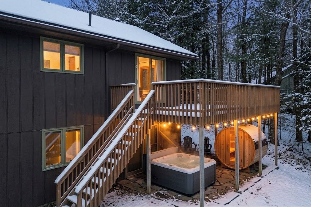 A wooden cabin with a hot tub, a deck, and a sauna.