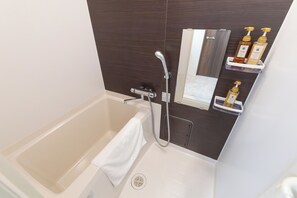 A modern bathroom with a bathtub, a shower, and a vanity with toiletries. - Ocean Namba West (Osaka)