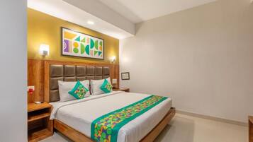 A hotel room with a large bed, wooden headboard, and a colorful abstract painting above the bed.