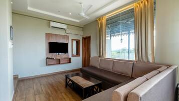 Sala de estar com sofá, mesa de centro, televisão de tela plana e ventilador de teto.