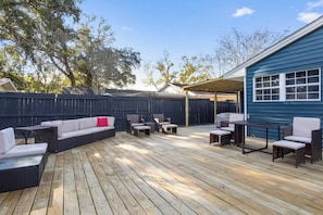 A wooden deck with outdoor furniture, including sofas and chairs, and a covered area with a grill. - Bible Themed Gulf Beach Escape (Gulfport)