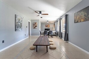 A spacious hallway with a dining area, ceiling fans, and artwork on the walls. - Bible Themed Gulf Beach Escape (Gulfport)