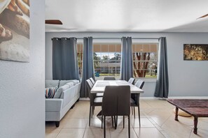 A dining area with a table and chairs, a sofa, and a view of the outdoors. - Bible Themed Gulf Beach Escape (Gulfport)