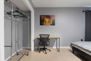 A bedroom with a bed, a desk, a chair, a wardrobe, and a painting on the wall. - Bible Themed Gulf Beach Escape (Gulfport)