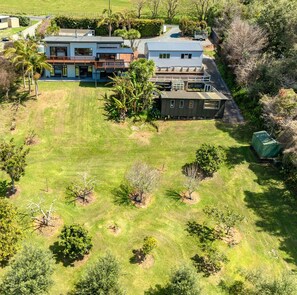 Imóvel residencial com gramado extenso, casa de dois andares e garagem separada.