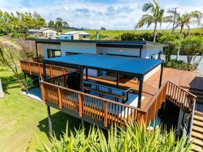Una casa de dos pisos con una terraza y un espacio exterior cubierto.