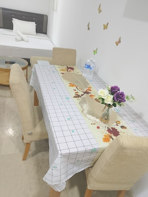Una habitación de hotel con cama, una mesa de comedor con sillas y un florero con flores.