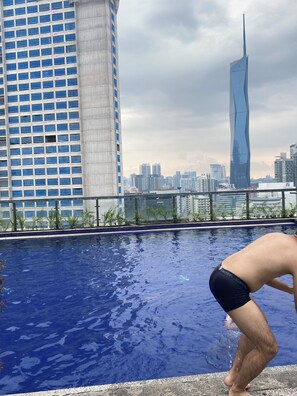 A swimming pool with a cityscape in the background, including a tall building with a unique design. - kualalumpur Bukit Bintang Fairlane Residence Rooftop Swimming Pool (Kuala Lumpur)
