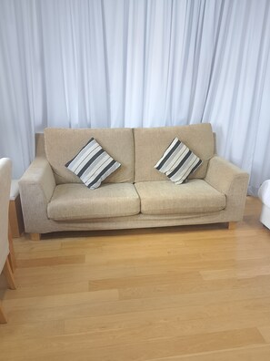 A beige sofa with two striped pillows against a white curtain backdrop. - kualalumpur Bukit Bintang Fairlane Residence Rooftop Swimming Pool (Kuala Lumpur)