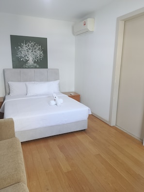 Habitación de hotel con cama, mesita de noche, control remoto y aire acondicionado instalado en la pared.