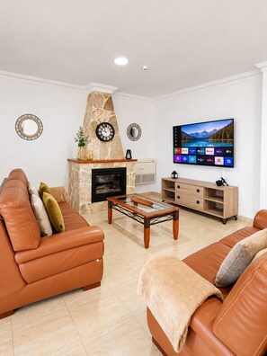 A living room with a fireplace, a television mounted on the wall, and a sofa. - Villa Hills Meloneras (Maspalomas)