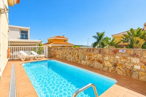 A swimming pool with a stone wall, a lifebuoy, and a sign indicating a depth of 1.10m. - Villa Hills Meloneras (Maspalomas)