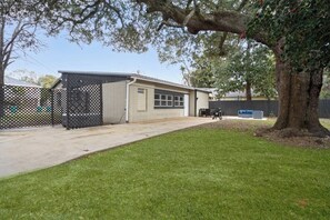A residential property with a single-story brick house, a covered patio, and a fenced backyard. - MineCraft Themed House - Hot Tub - King Bed (Gulfport)