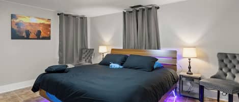 A hotel room with a bed, two bedside lamps, a chair, a painting, and a ceiling light.
