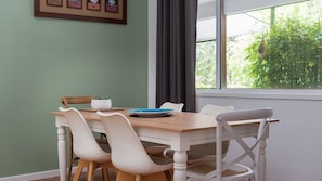 A dining area with a table, chairs, and a window with a view of greenery. - Grant Street Getaway (Port Macquarie)