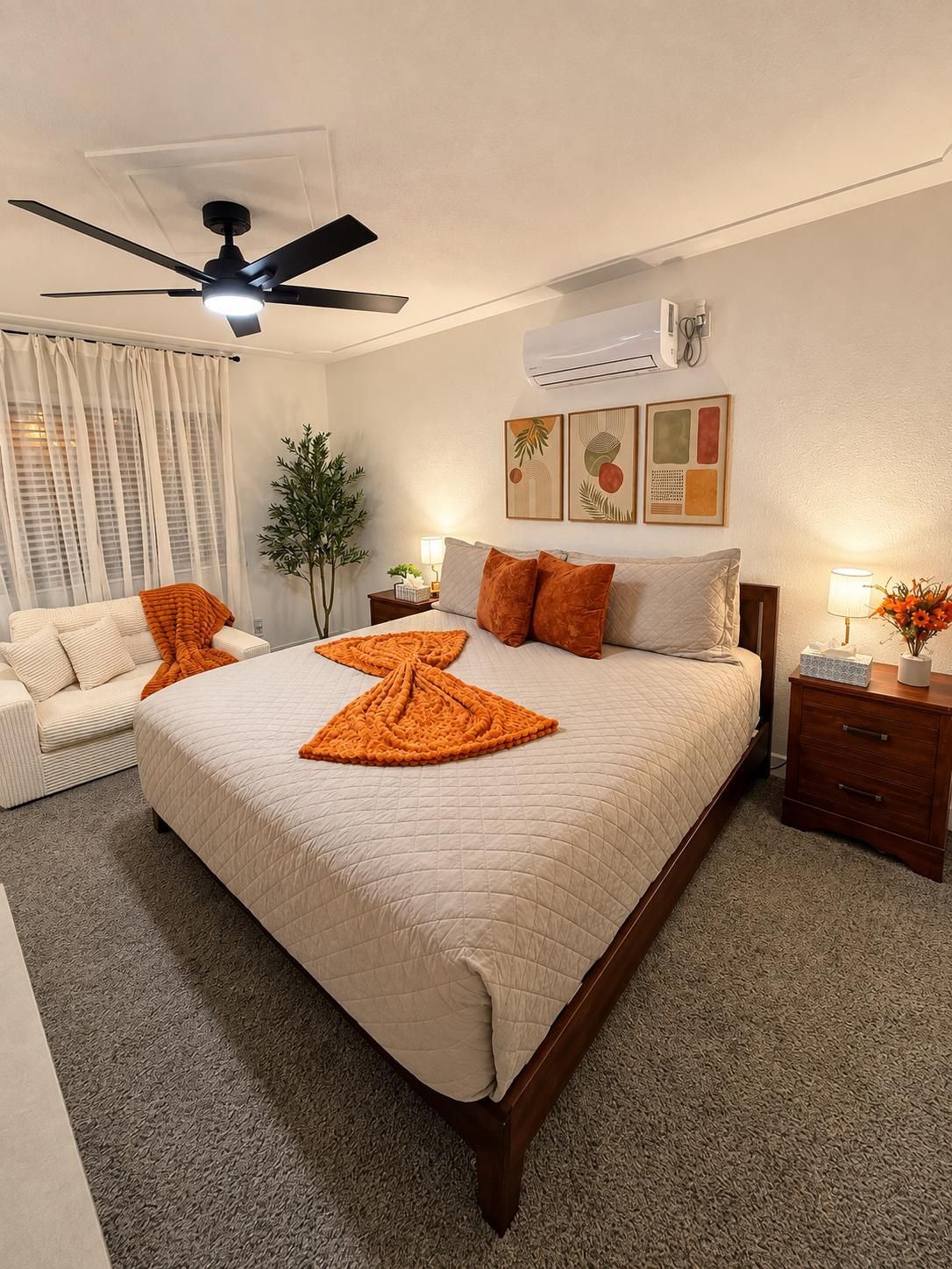 Ein Hotelzimmer mit einem Bett, einem Deckenventilator, einem Nachttisch, einer Lampe und einem Fenster mit Vorhängen.