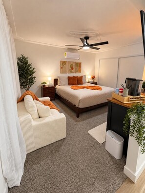 Un dormitorio moderno con cama, mesitas de noche, escritorio y ventilador de techo.