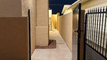 A gated pathway leading to a building at night with exterior lighting.