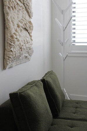 Een kamer met een bed, een textuurrijk object aan de muur en een raam met jaloezieën.
