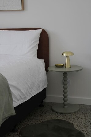 Ein Schlafzimmer mit einem Bett, einem Nachttisch mit Lampe und einer kleinen Schale darauf.