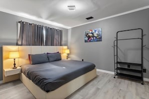Ein Schlafzimmer mit einem Bett, zwei Nachttischen mit Lampen, einem Wandregal und einem Gemälde.