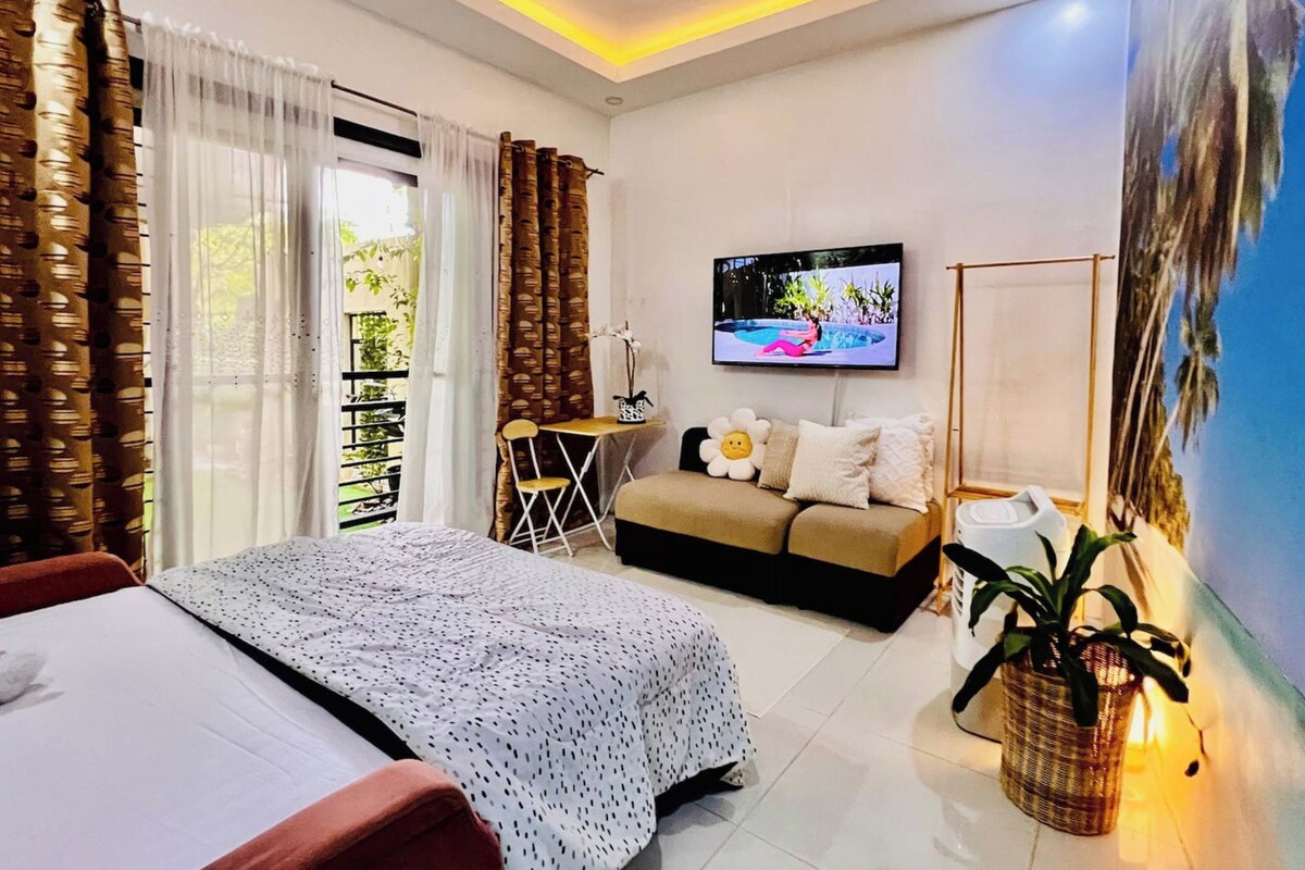Ein modernes Hotelzimmer mit Bett, Sofa, Fernseher und einem großen Fenster mit Vorhängen.